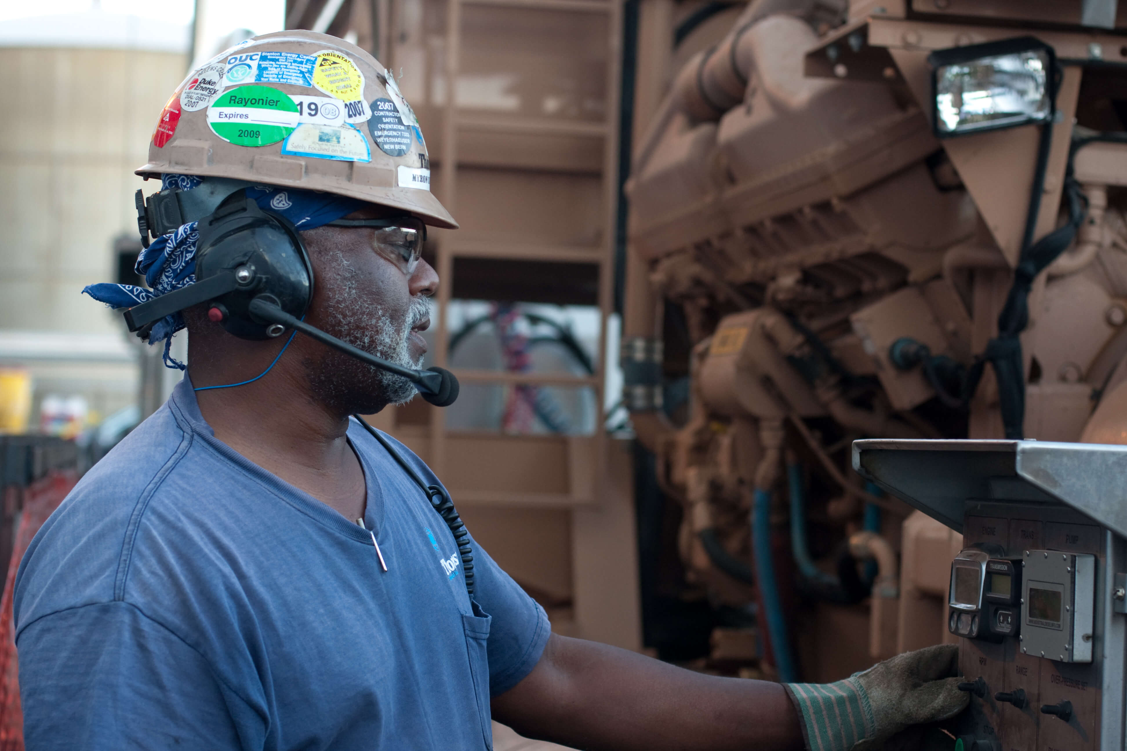 Maintenance worker on an industrial site fixing heavy machinery wearing a hard hat on an industrial construction site in South Carolina.